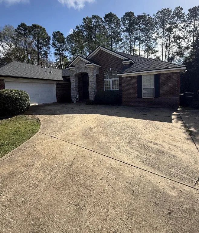 Before: residential driveway cleaning in front of a brick home