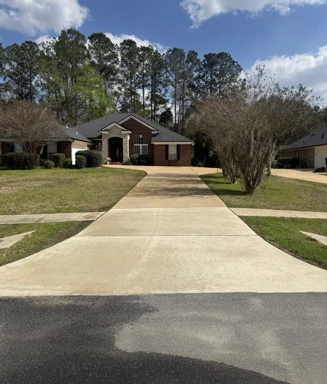 After: residential driveway cleaning in front of a brick home