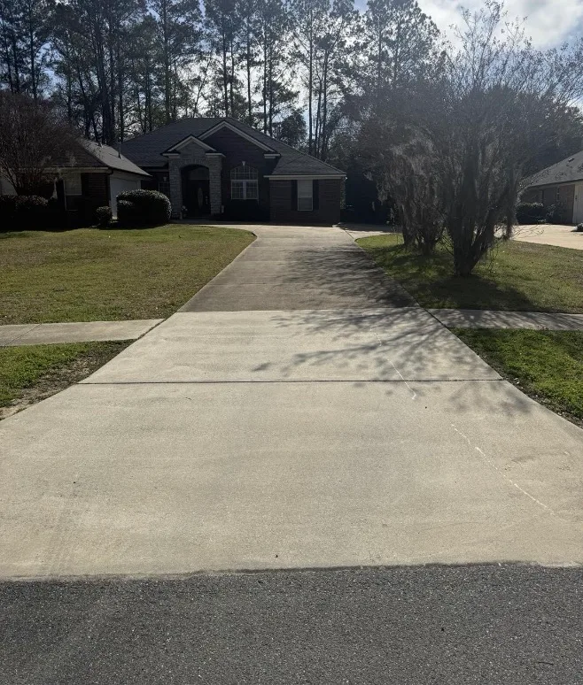 Before: residential driveway cleaning in front of a brick home