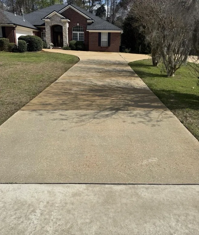 After: residential driveway cleaning in front of a brick home
