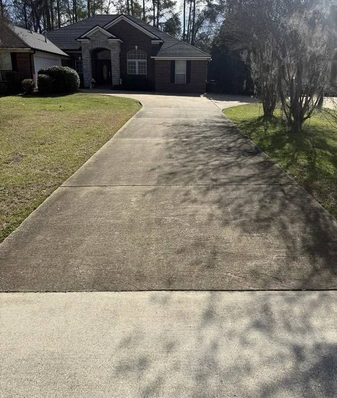 Before: residential driveway cleaning in front of a brick home