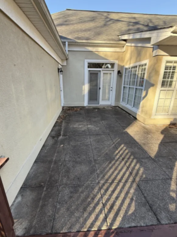 Before: residential courtyard patio cleaning, dark buildup removed from the pavers